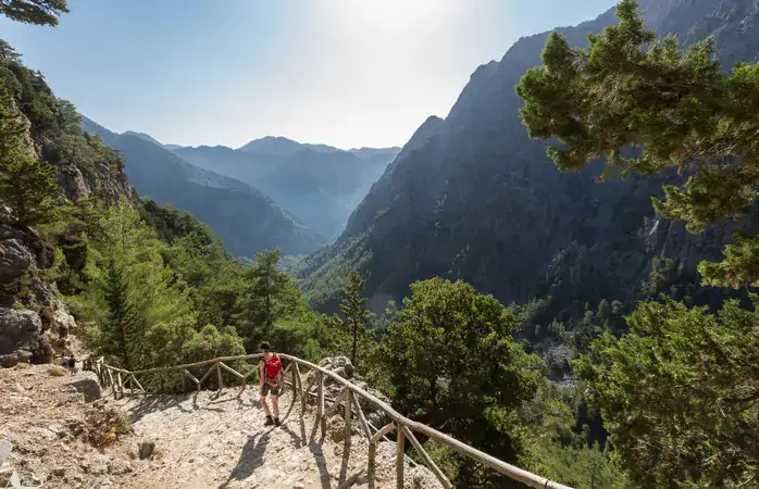 A woman on her way down to the entrance of Samaria Gorge, Crete. The gorge is in southwest Crete in the regional unit of Chania and a major tourist attraction of the island. It was created by a small river running between the White Mountains and Mt. Volakias. The gorge is 16 km long, starting at an altitude of 1,250 m (4100 ft.)at the northern entrance, and ending at the shores of the Libyan Sea in Agia Roumeli.